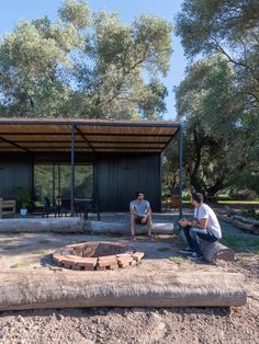 two men are sitting around a fire pit