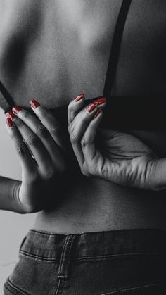 a black and white photo of a woman with red nails holding her hands on her chest