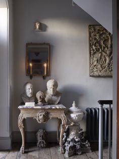 a table with statues on it in front of a mirror and radiator next to a wall