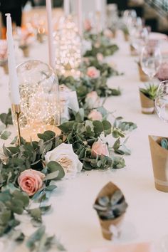 the table is set with candles and flowers on it, along with napkins and place settings