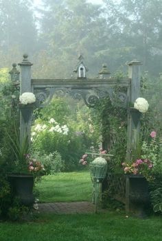 a garden with lots of plants and flowers on the ground in front of an archway