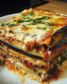 a white plate topped with lasagna covered in sauce and cheese