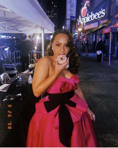 a woman in a pink dress eating a donut