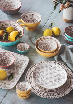 a table topped with plates and bowls filled with lemons