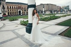 a woman in a wedding dress standing next to a pole