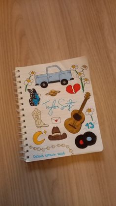 a notebook with stickers on it sitting on top of a wooden table next to a pen