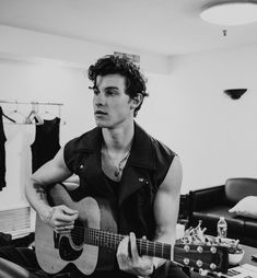 a young man sitting on the floor playing an acoustic guitar