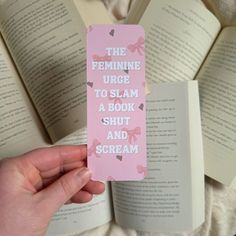 a person holding up a bookmark that says the feminine urge to slam a book shut and scream