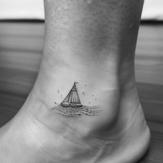 a small sailboat on the ankle tattoo is seen in this black and white photo