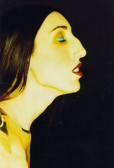 a woman with long black hair and blue eyes is looking up at something in the air