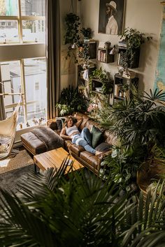 a man laying on top of a couch in a living room next to a window