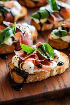 bread topped with prosciutto and cheese on a wooden cutting board next to other appetizers