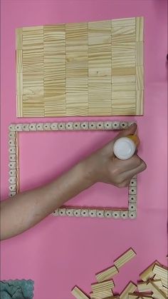 a person's hand is holding a small object in front of wooden pegs