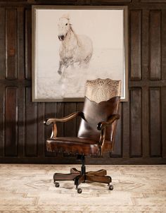 an office chair sitting in front of a painting on the wall next to a wooden desk