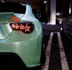 two cars parked next to each other in a parking lot at night with lights on them