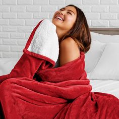 a woman laying on top of a bed covered in a blue blanket and covering her face with a white towel