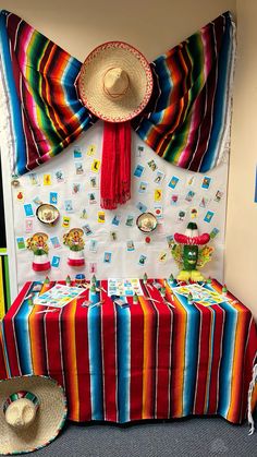 a table with a colorful blanket and hat on it in front of a wall decoration