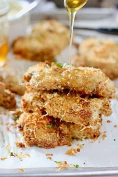 some fried food is being poured on top of it with oil and seasoning in the background