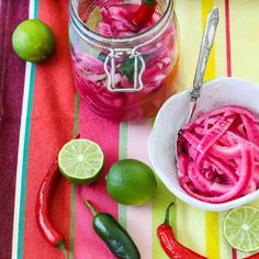 red onions and limes in a bowl next to a jar of pickled peppers