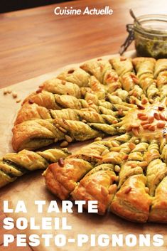 a pizza sitting on top of a wooden table next to a jar of pesto