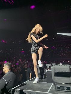 a woman standing on top of a stage in front of a crowd at a concert