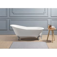 a white bath tub sitting on top of a hard wood floor next to a wooden table