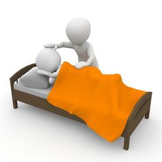 two people are sitting on a bed with an orange blanket over the bed and one person is standing up