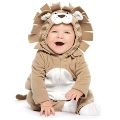 a baby in a lion costume sitting on the ground with its mouth open and tongue out