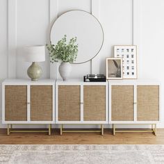 a white cabinet with wicker doors and a round mirror on top next to a lamp