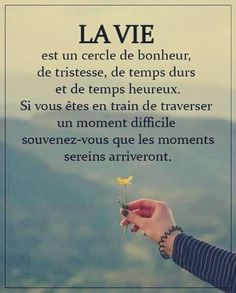 a person holding a flower in their hand with the words la vie on it and mountains in the background