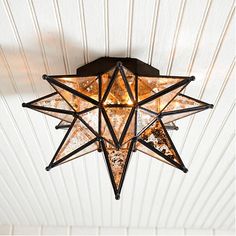 a star light hanging from the ceiling in a room with white walls and wood paneling