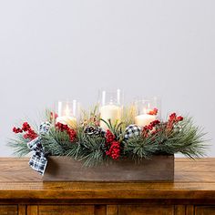 a wooden table topped with candles and greenery