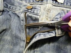 someone is cutting through the back pocket of their jeans with a pair of purple scissors