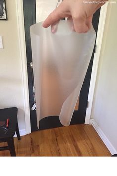 a person is holding a plastic bag in front of a door and pointing at it