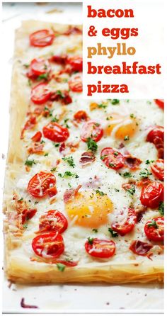 bacon and eggs phylo breakfast pizza on a sheet of parchment paper with cherry tomatoes