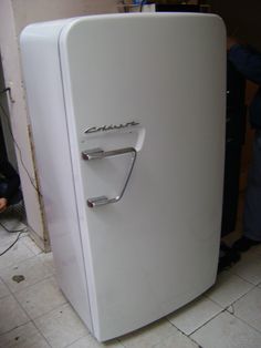 a white refrigerator sitting on top of a tiled floor