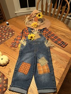 a child's overalls and hat sitting on top of a wooden table next to pumpkins