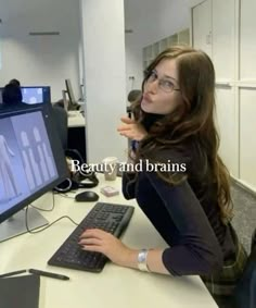 a woman sitting in front of a computer with the words beauty and brains on it