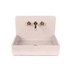 a white sink with two brass faucets on the front and bottom, against a white background