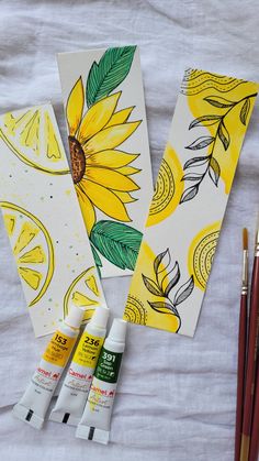 three lemons and two sunflowers are next to some watercolor pencils