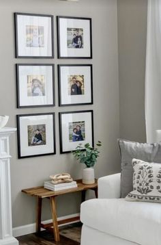 a living room with white furniture and pictures on the wall above it's fireplace