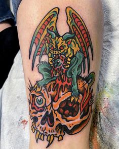 a tattoo on the leg of a person with a dragon and skull design on it