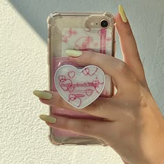 a woman's hand holding an iphone case with a heart shaped sticker on it