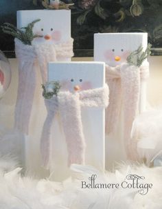 three snowmen made out of white boxes sitting on top of fluffy white fur covered ground