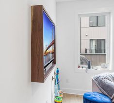 there is a television mounted on the wall in this living room with a blue footstool