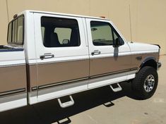 a white and brown truck parked in front of a building with no one on it