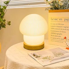 a table topped with a white lamp next to a book