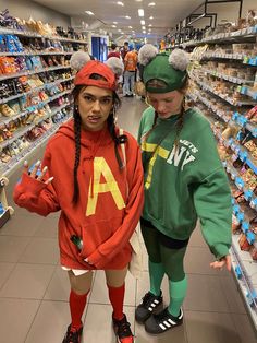 two girls in costumes standing next to each other at a grocery store with shelves full of food