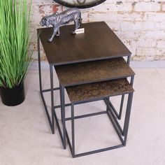 three nesting tables with a metal dog figurine on top and grass in the background