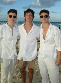 three men standing next to each other on a beach